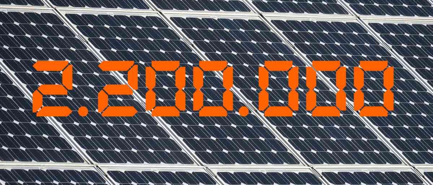 Die Zahl 2,2 Millionen in Orange vor einem Hintergrund aus Solarpaneelen - Photovoltaik